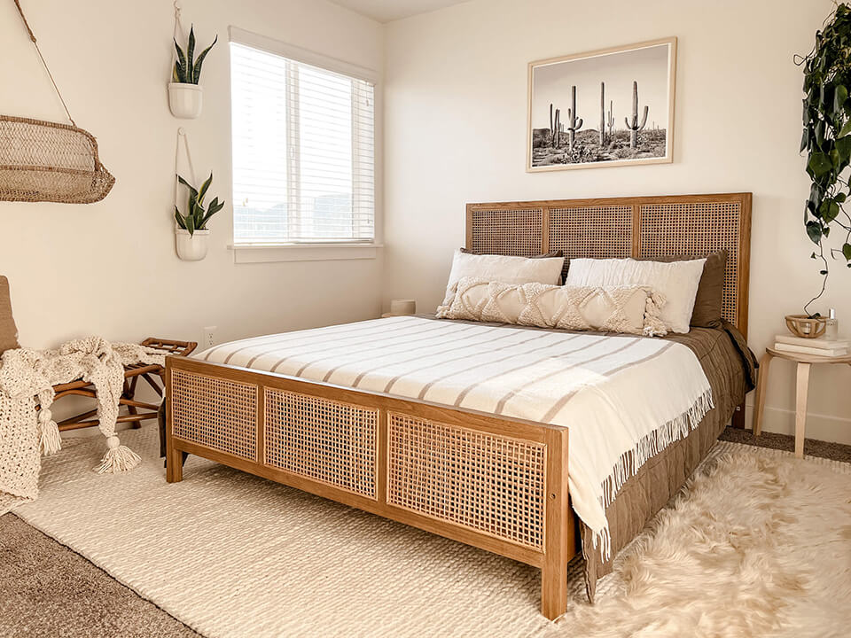 An inviting bedroom featuring a comfortable bed, a decorative rug, and a touch of greenery with a potted plant.