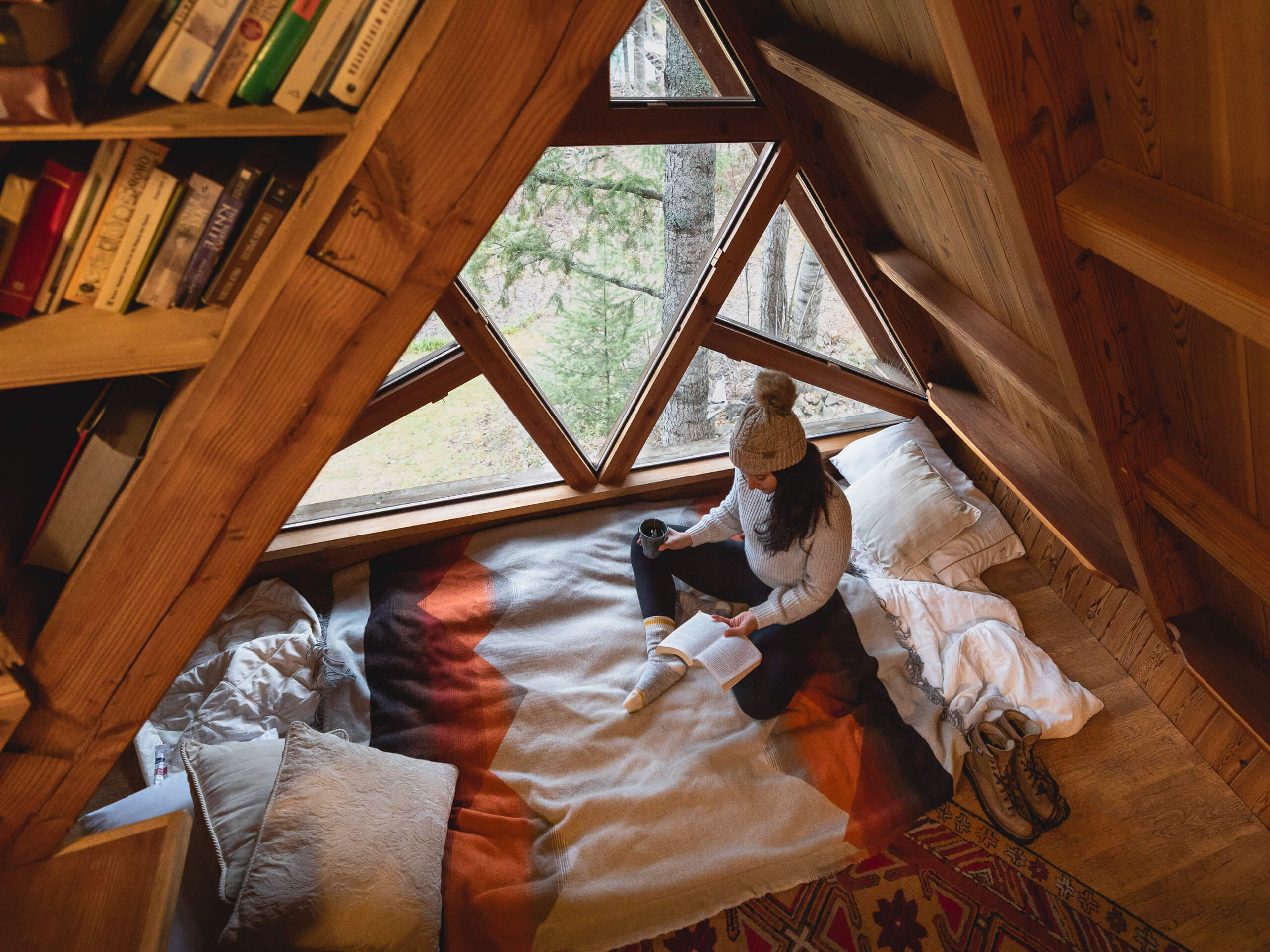A woman sitting on a bed in a cozy tiny house, enjoying the comfort and simplicity of her surroundings.